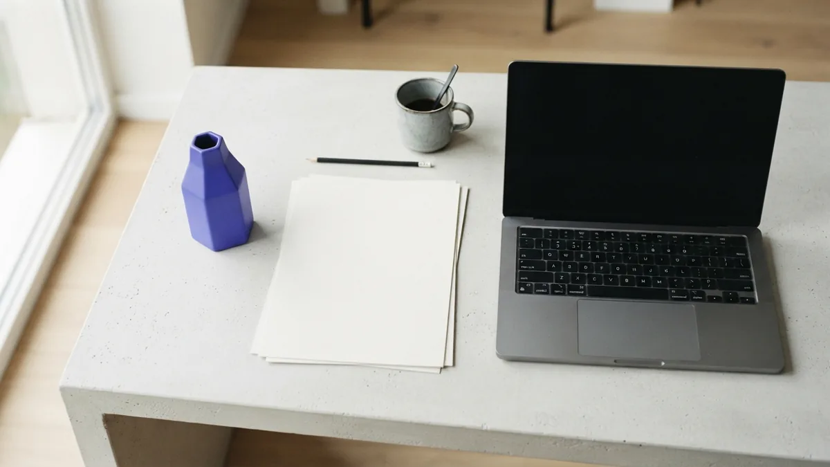 Blank design sheets beside a closed laptop in a bright portfolio workspace